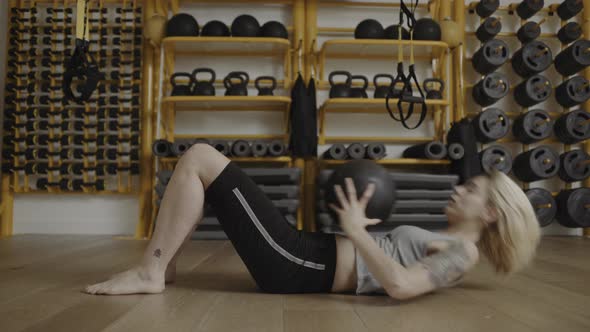 Young woman doing abdominal exercises with ball in gym