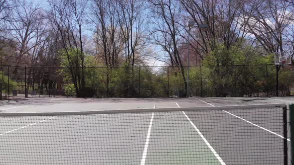 Drone footage at tennis court flying parallel to the tennis net outdoors alt