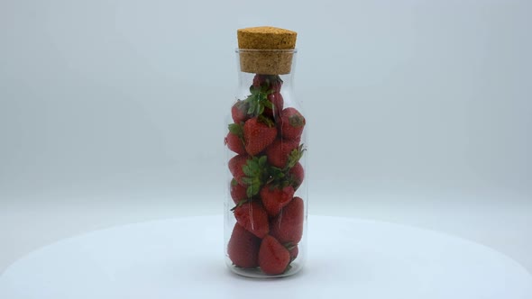 Strawberries in a clear bottle rotating on a white background. Strawberry ripe season