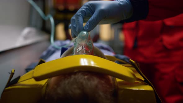 Paramedic Hand in Glove Holding Oxygen Mask on Patient Face in Emergency Car alt