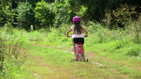 A little girl rides a Bicycle . Bright Sunny summer day outdoors.