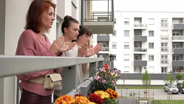 Three Women Stand on the Balcony of an Apartment Building and Applaud Joyfully. People Are Happy alt