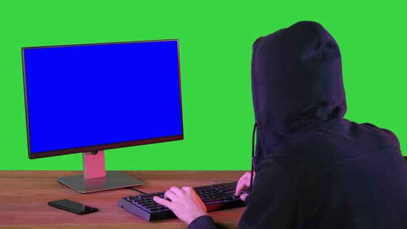 Hacker in Hood Cracking Code Using Pc on a Green Screen Chroma Key alt