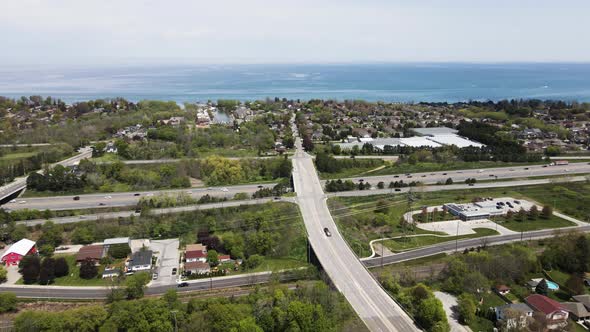 Aerial pan shot showing bridge road following over asphalt highway towards Lake Ontario during summe alt