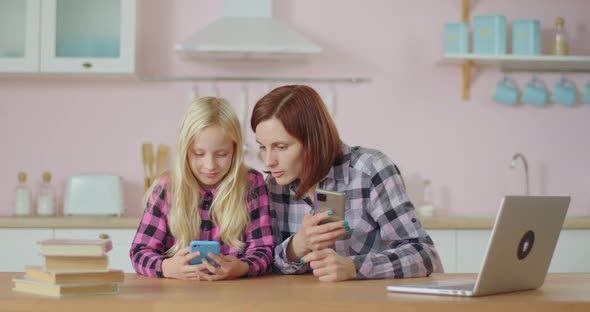 Young Adult Woman and Preteen Girl Laughing While Watching Video at Mobile Phone Application. Family