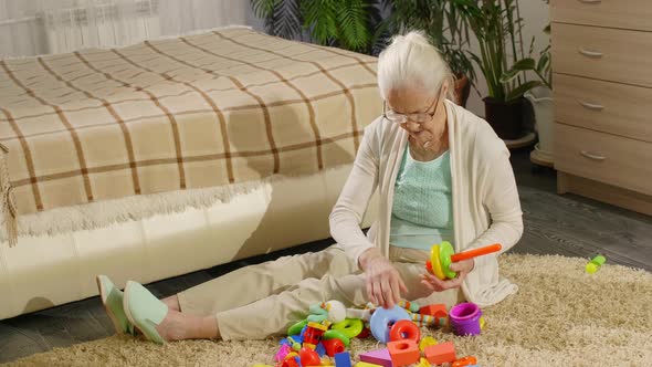 Grandmother Cleaning Up after Playing with Baby at Home