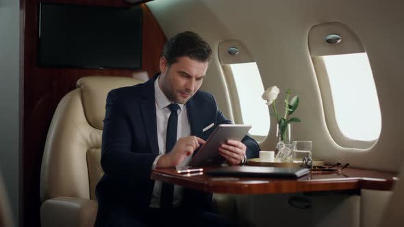 Stressed Businessman Working Tablet in Airplane alt