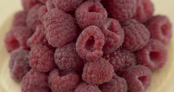 Ripe Raspberry Berries Piled on A Plate, Rotated Against a Black Background