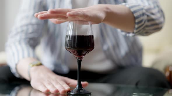Male Hand Covering Glass with Red Wine Standing on Glass Table alt
