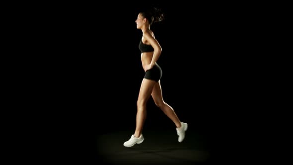 Young Athletic Woman Wearing Sporstwear is Exercising Isolated on Black