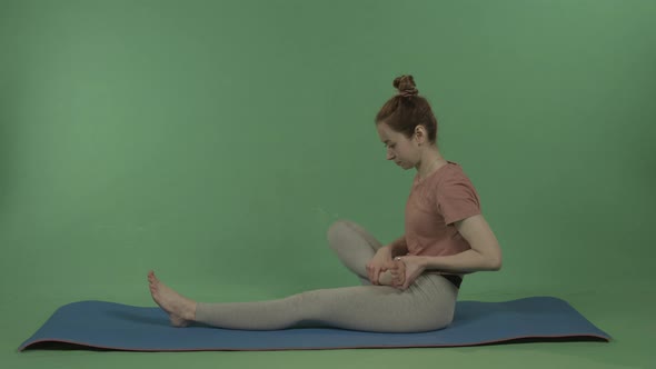 A Young Pretty Girl Does Yoga on a Background of Green Chromakey