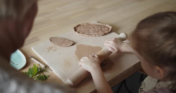 Grandmother Teaches Her Granddaughter to Mold Clay in Pottery Workshop alt