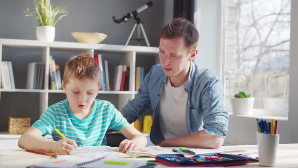Boy and Father Doing Homework at the Table. Child is Learning at Home. alt