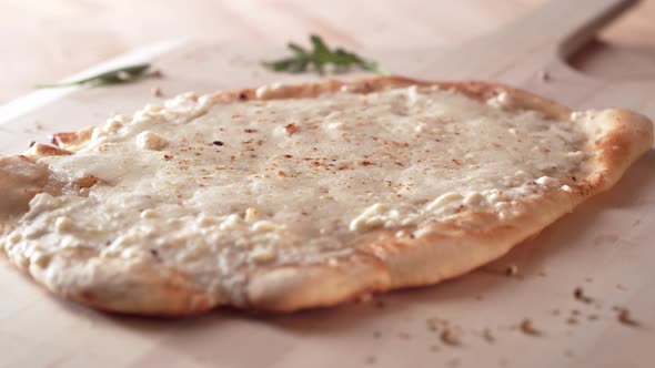 Camera follows putting slices of prosciutto on a white pizza. Slow Motion. alt