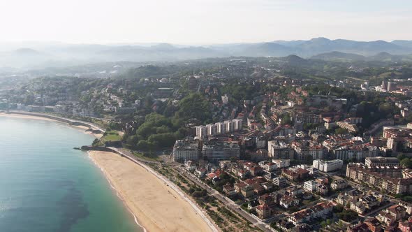 Sandy beach of San Sebastian city on coastline of Atlantic ocean, cinematic aerial view alt