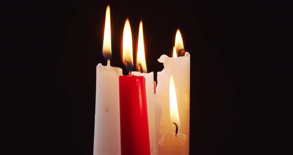 Burning White and Red Candles on a Black Background alt