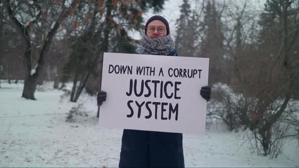 A man is holding a sign Down with a corrupt justice system. Single Protest. alt