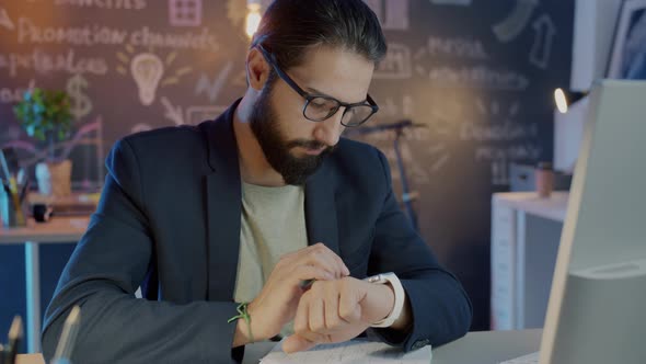 Slow Motion Portrait of Serious Businessman Using Smart Watch Working Late in Office alt