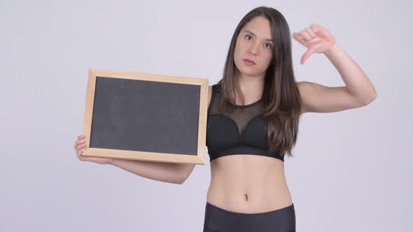 Young Stressed Woman Holding Blackboard and Giving Thumbs Down Ready for Gym alt