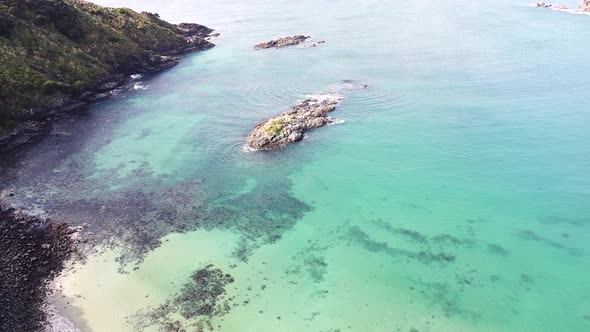Rising aerial drone of rocky outcrop in Maitai Bay Karikari Peninsula, Northland, New Zealand Aotear alt