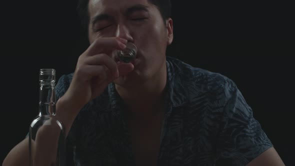Close Up Of Drunk Asian Man Cheering Vodka Glass To Camera Before Drinking In Black Background, Stock Footage