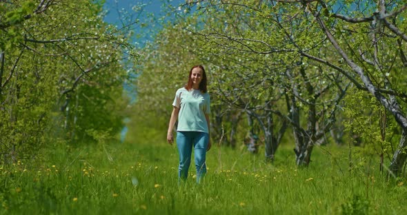 Young Woman is Walking in Blooming Garden in Spring Viewing Trees  Prores