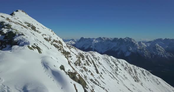 Aerial drone view of snow covered mountains in the winter. alt