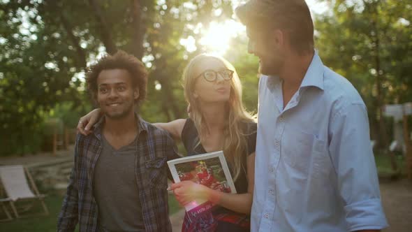 Bearded Cacucasian Male Embracing Blonde Female Walking with Darkskinned Man with Afro Hairstyle in alt