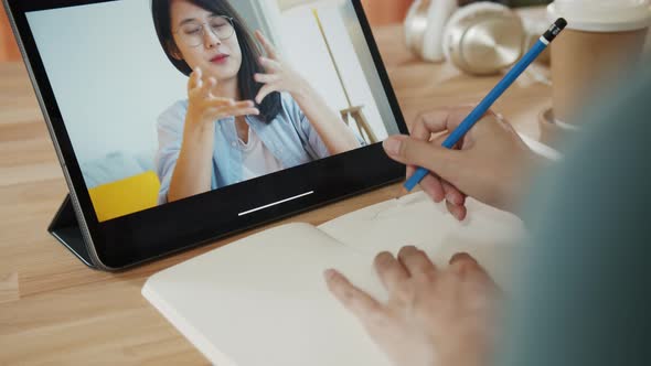 Asian Businesswoman taking notes while having a video call conference