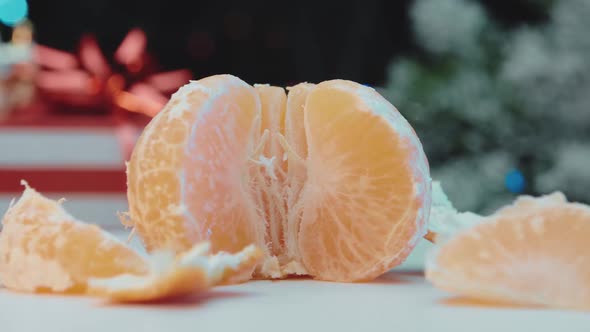 The peeled mandarin is spinning in a circle against the background of New Year's gifts