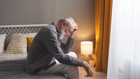 Sad Senior Man Looking Down with Anxiety Thinking About Something Sad