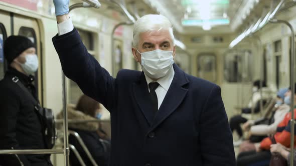 Old Person in Face Mask with Gloves Stands with Several People in Tube Carriage