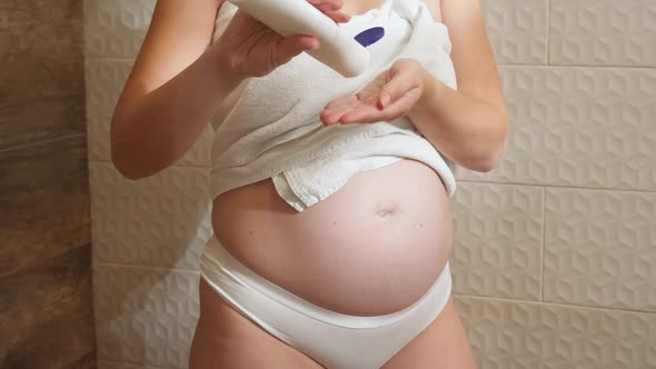 Closeup of Pregnant Woman Applying Moisturizing Creme on Body Skin After Having Shower in Bathroom alt