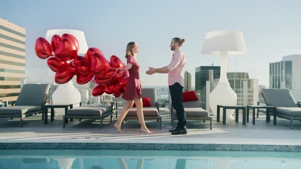 Happy Young Woman with Red Balloons Walking at Pool on Rooftop of Modern City alt