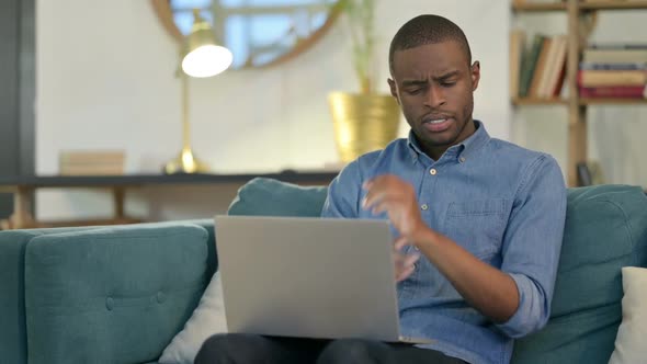 Young African Man with Laptop Having Wrist Pain on Sofa alt