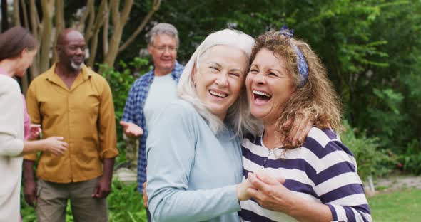 Animation of happy diverse female senior friends embracing in garden alt