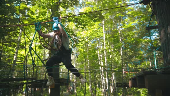 Woman Crossing a Rope - an Entertainment Attraction in the Forest for Young People alt
