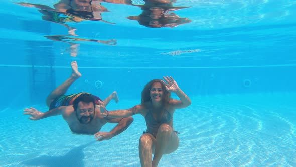 Happy caucasian people couple have fun and enjoy the swimming activity at the pool alt