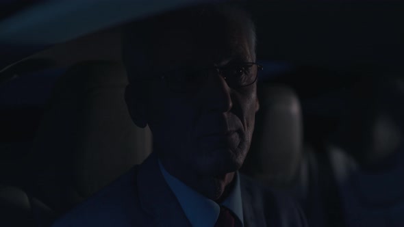 Old Businessman Rides in the Back Seat of a Car alt