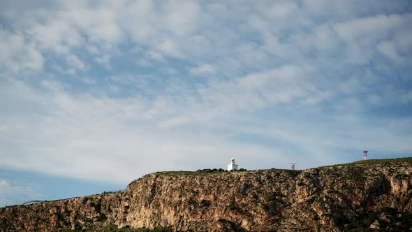 Clouds Over Lighthouse On Cliff In Spain. Timelpase alt
