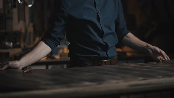Close Up of Unrecognizable Male Craftsman Smoothing Leather Piece on Table at His Workshop Tracking alt
