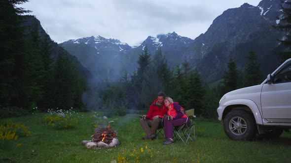 Couple Chatting By Bonfire in a Camping in a Dark Mountain Valley White Car