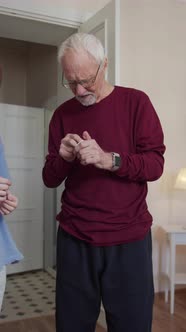 The Trainer Helps an Elderly Man Put on Wireless Headphones and Plays a Workout Video on a Laptop
