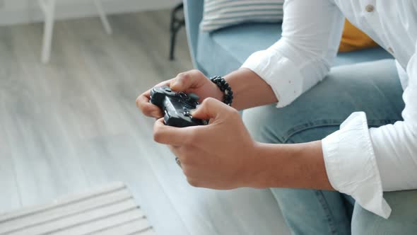 Close-up of Emotional Mixed Race Man Playing Video Game Pressing Joystick Buttons at Home alt