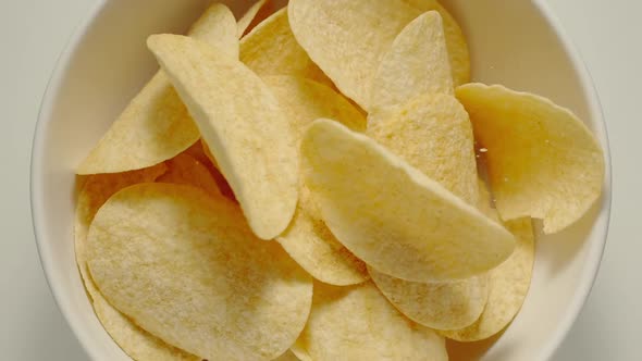 Potato crisps falling into a white bowl
