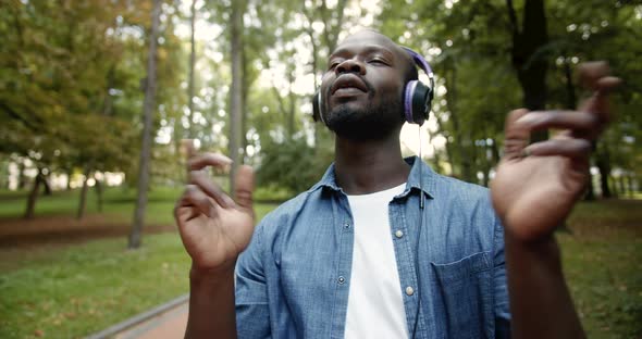 Happy Dancing Afro-American in Earphones in Park