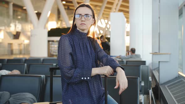 Businesswoman Watching of the Plane Standing at the Airport Window at Sunset in the Evening