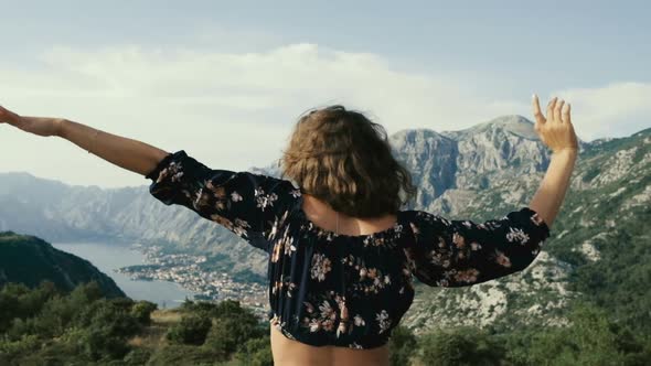Young curly-haired woman in sunglasses on the background of the mountains alt