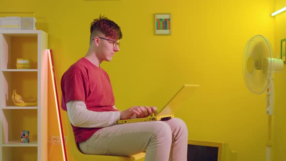 Man In Eyeglasses Is Typing On Yellow Laptop