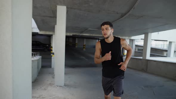 Athlete Runs Around By Levels of an Empty Parking Garage Front View alt